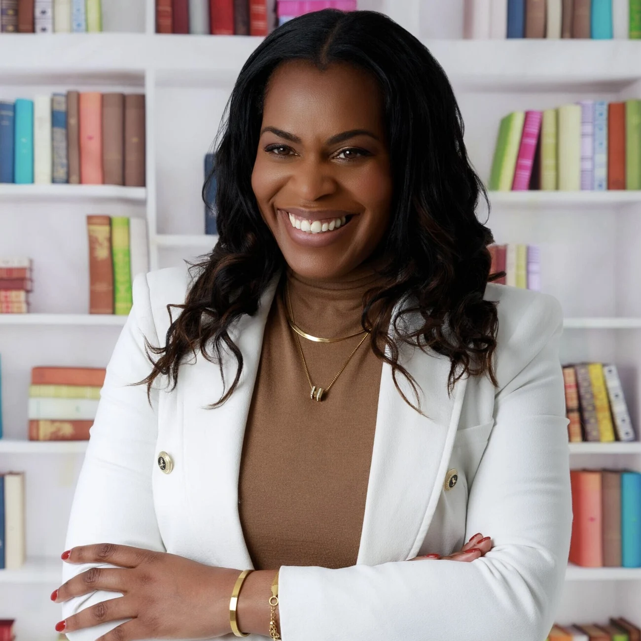 Emma Noel Pinnock smiling, standing in front of bookshelves